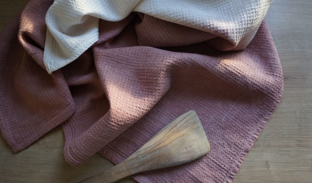 dusty pink and white linen waffle kitchen towels and a wooden spatula