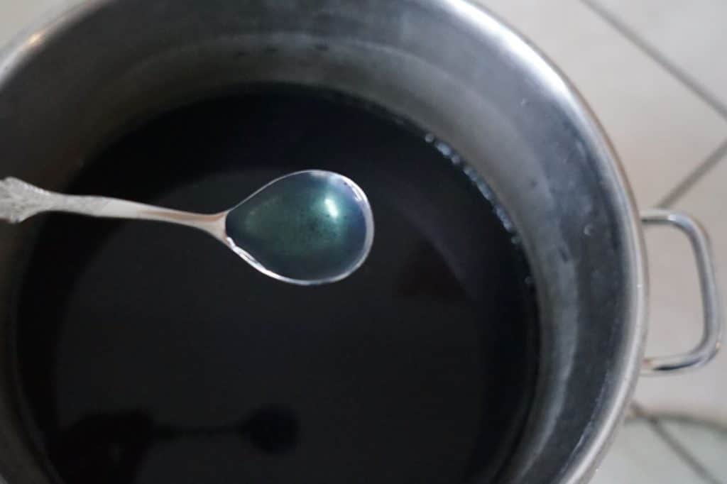 teaspoon with indigo vat solution over a indigo vat in a pot