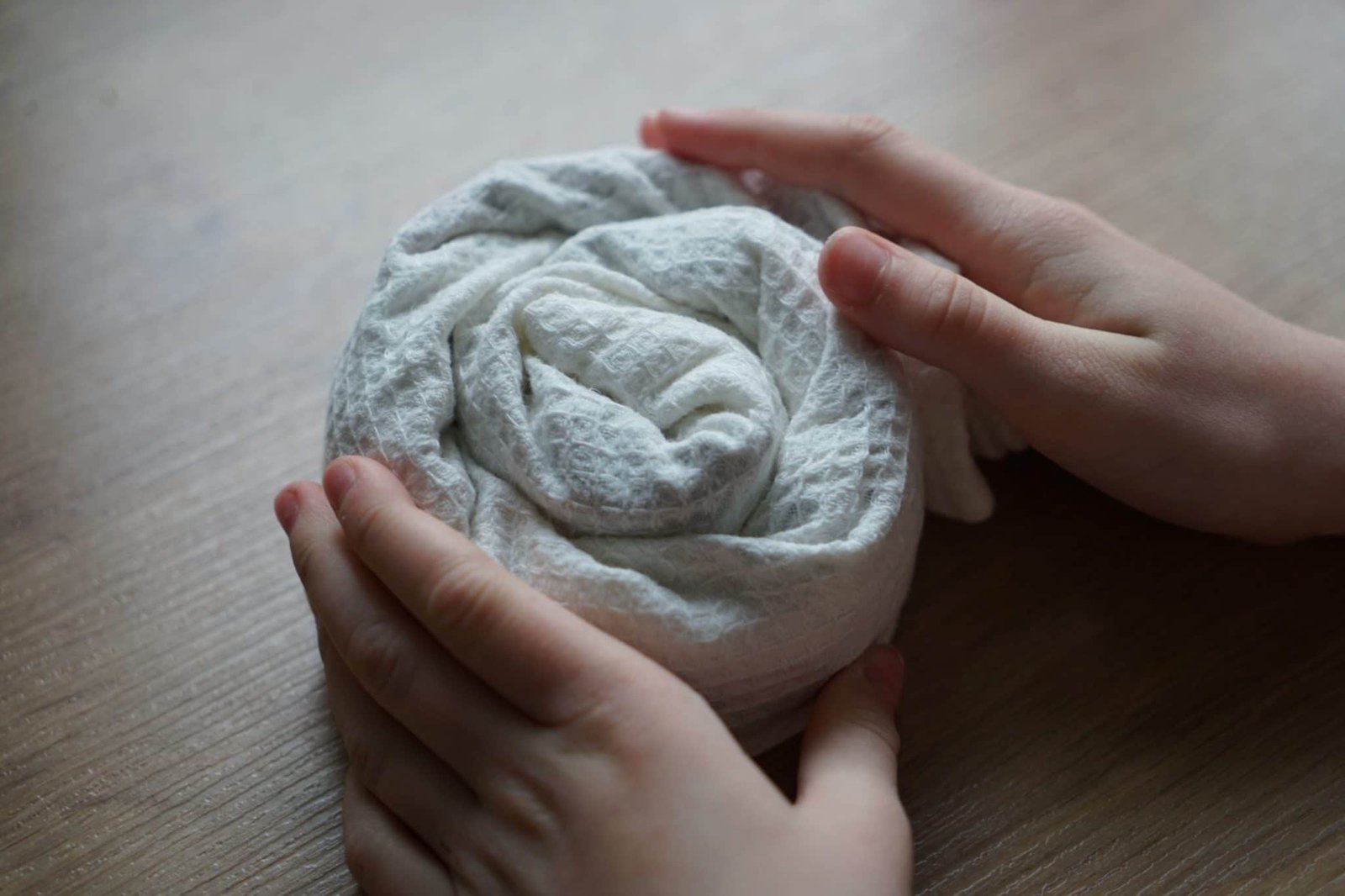 kitchen towel rolled up in a bundle held together by two small hands