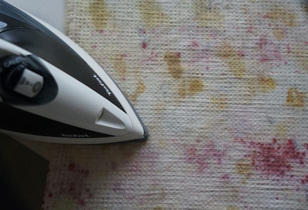 ironing a kitchen towel with splashes of color all over it