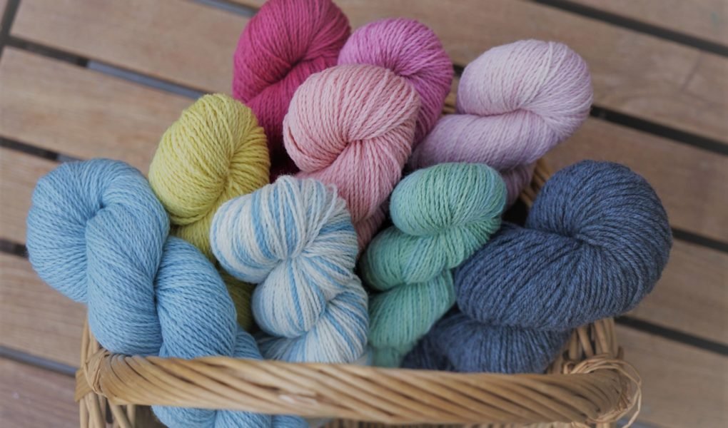 nine colorful skeins of yarn in a basket