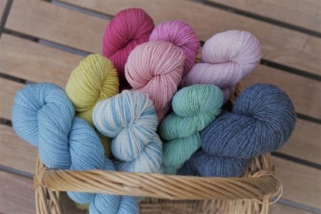 nine colorful skeins of yarn in a basket