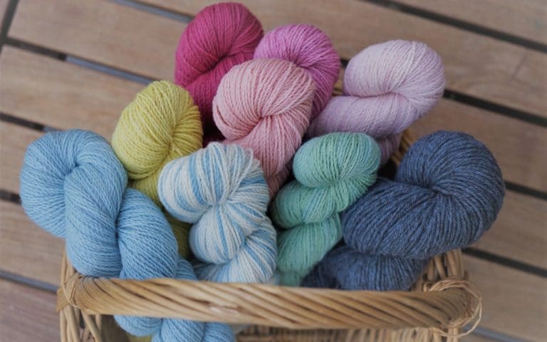 nine colorful skeins of yarn in a basket