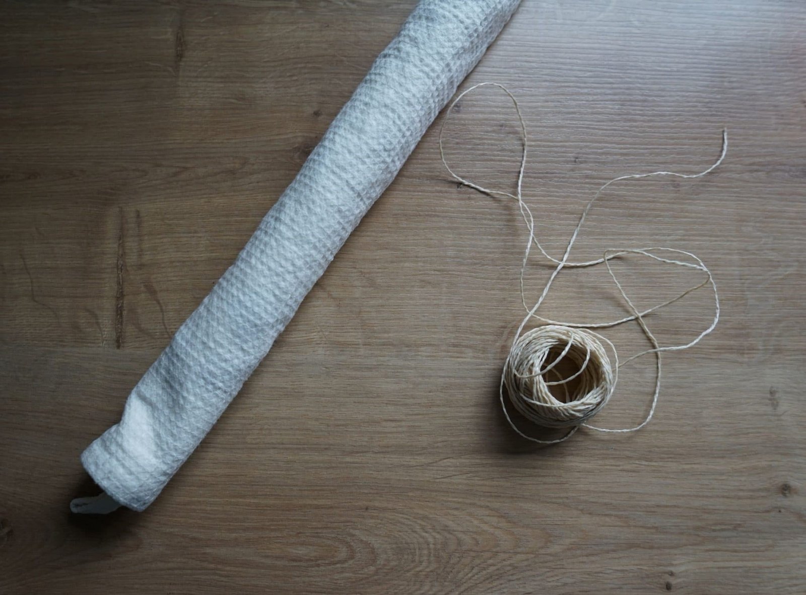 rolled up kitchen towel and some packaging twine on a wooden surface