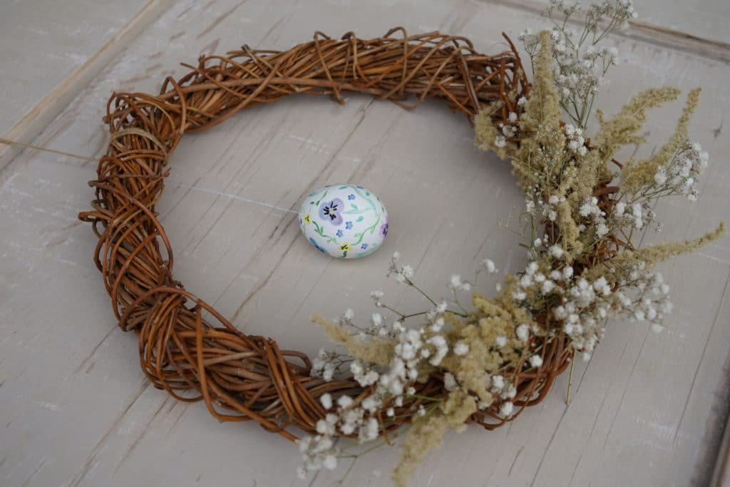 willow wreath decorated with glysophila and goldenrod and an hand painted easter egg