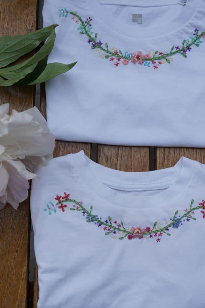 two embroidered cotton shirts and a light pink peony on a wooden table