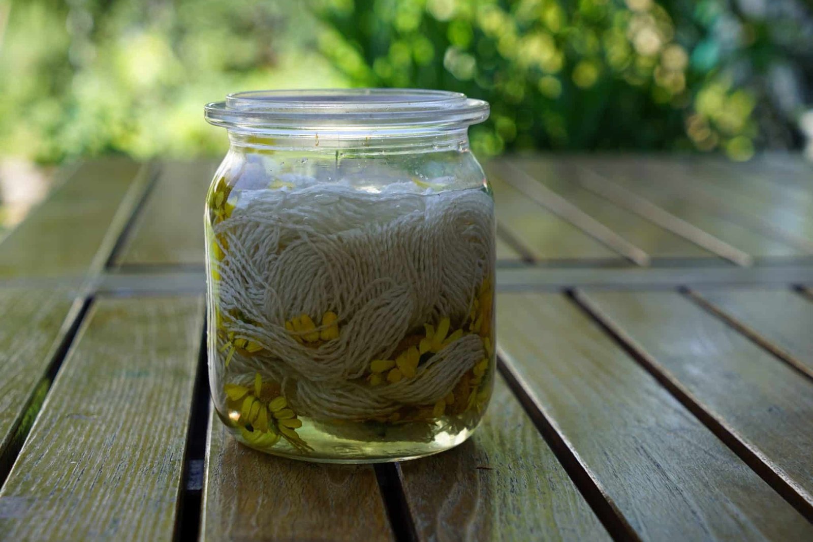 glass jar filled with yarn and yellow flowers