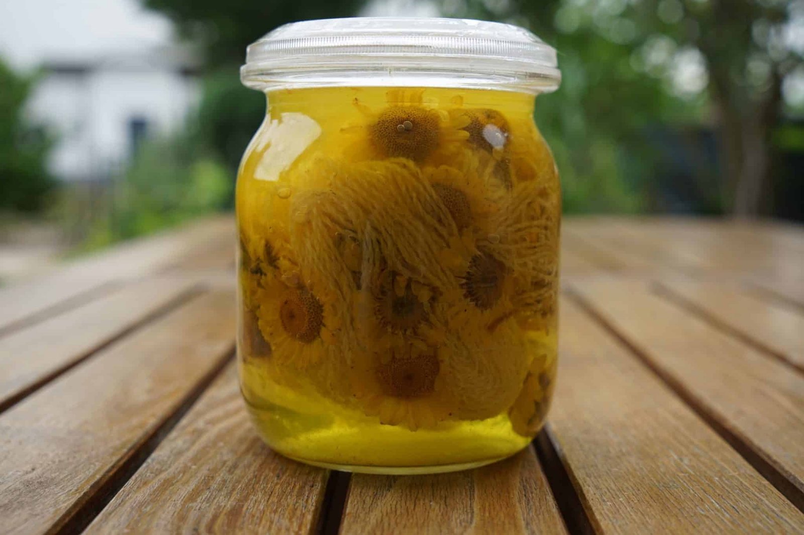 glass jar filled with yarn, yellow flowers and a yellow dye solution