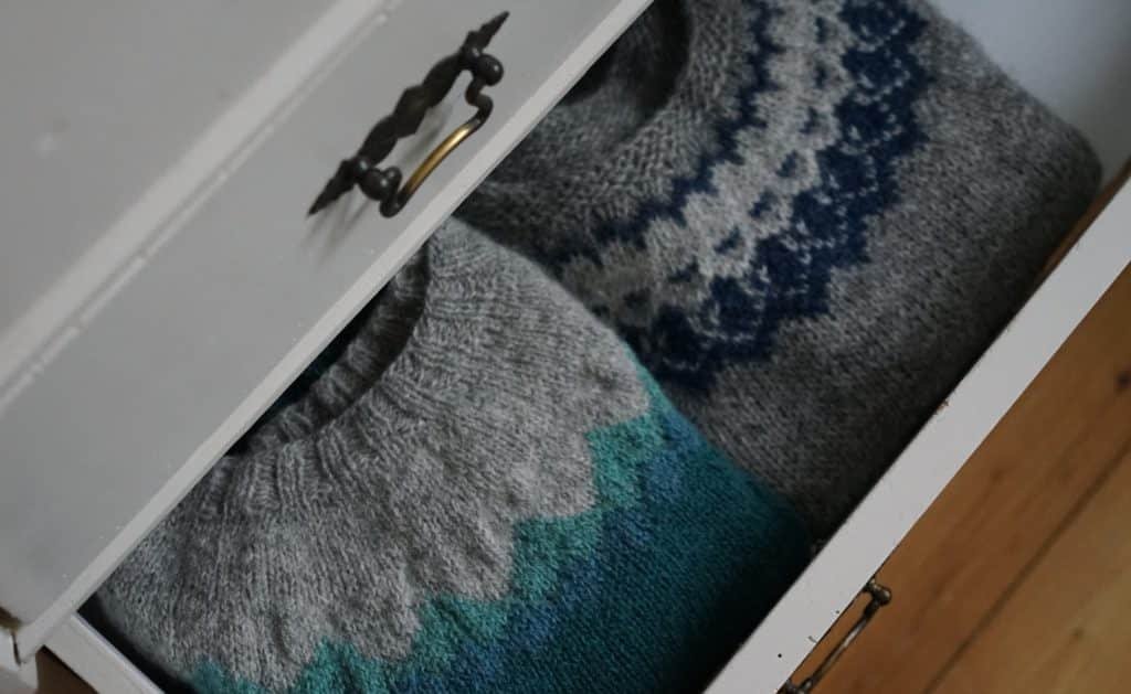 two colourful sweater in a white dresser