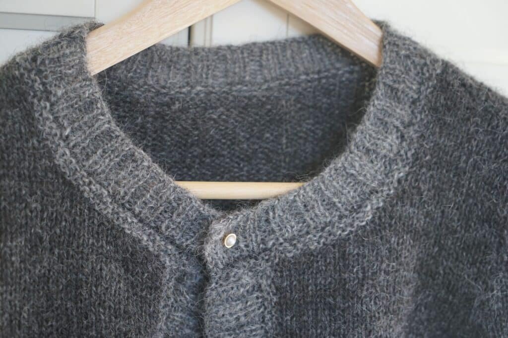 upper part of handknitted grey cardigan on a hanger