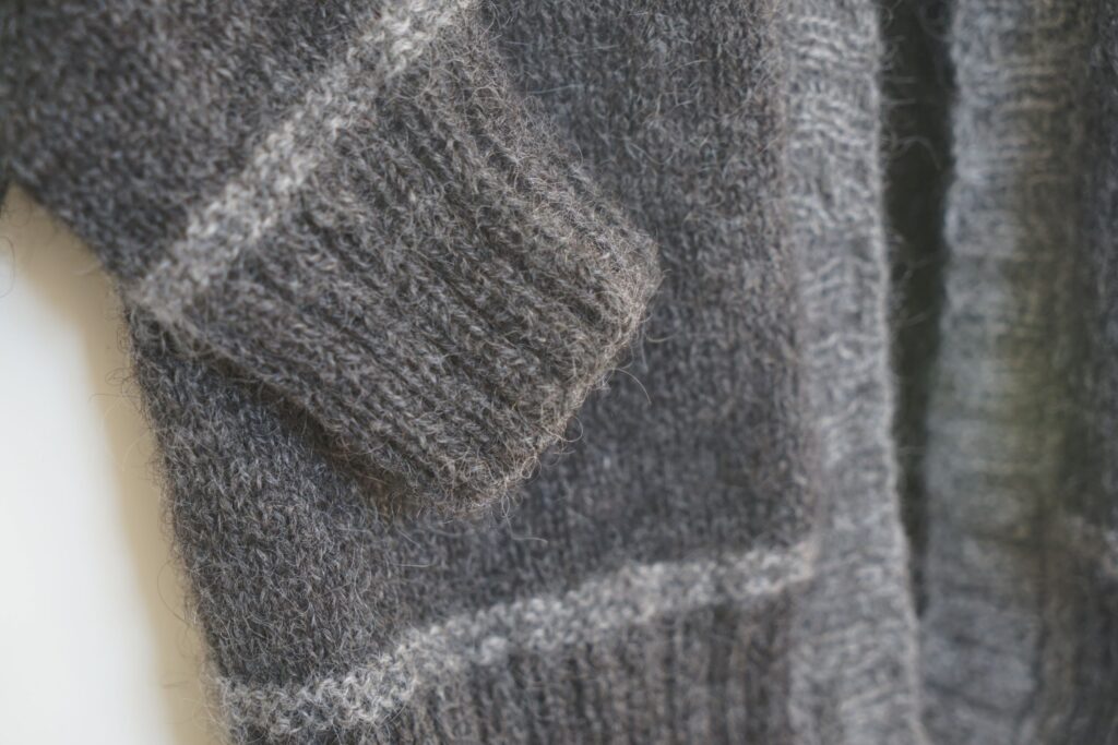 cuff detail of a dark and light grey knitted cardigan