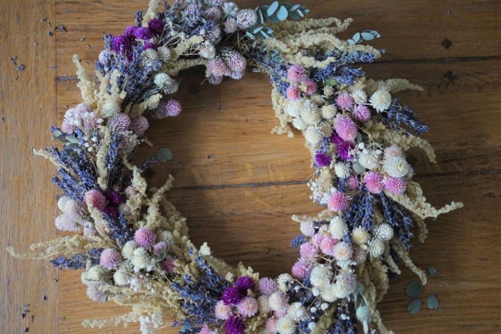 dried flower wreath in purple, pink, white and yellow on a wooden table