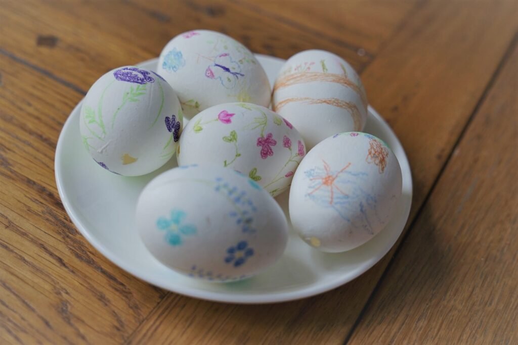 five eggs painted with pencils laying on a small white plate