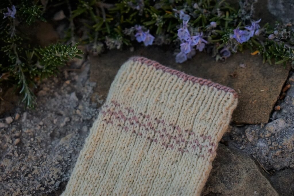 soft yellow and pink handknitted socks, only the cuff is showing