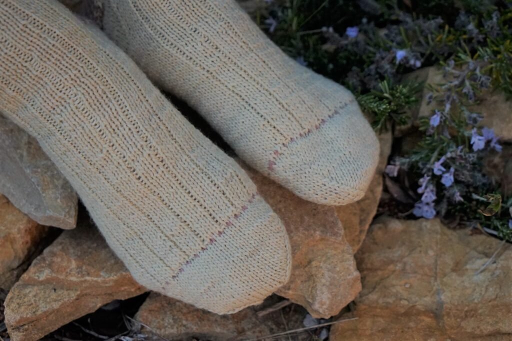 soft yellow and pink handknitted socks, only the feet are showing