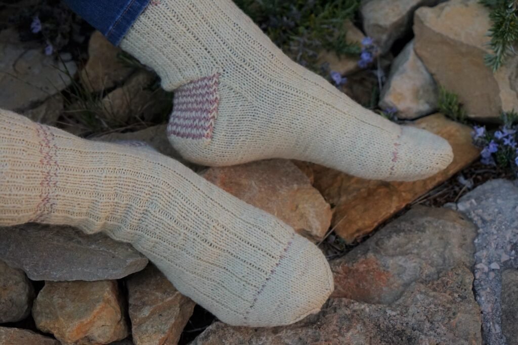 two feet in handknitted socks in a garden