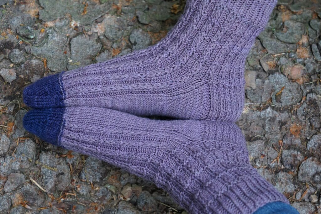 handknitted purple socks on a tree trunk