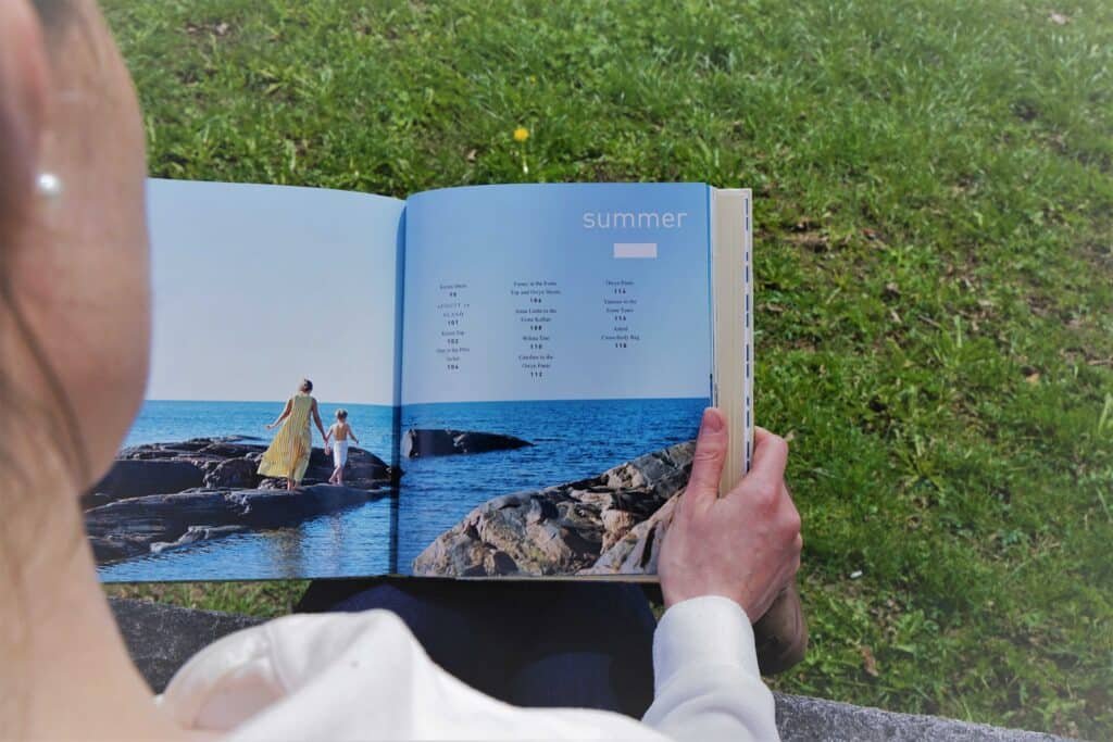 a woman holding a book with a page title called "summer"