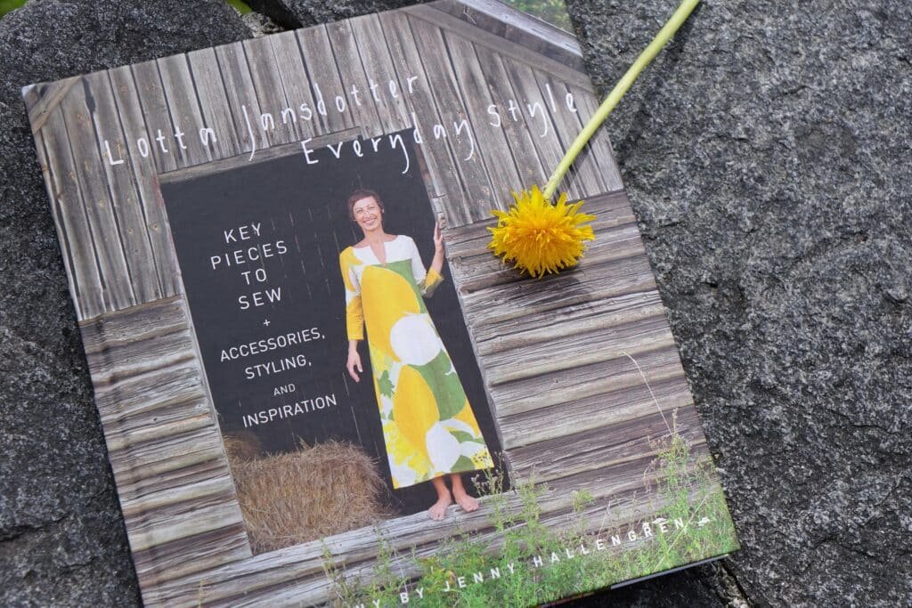 book everyday style by lotta jansdotter on a stone wall next to a dandelion bloom