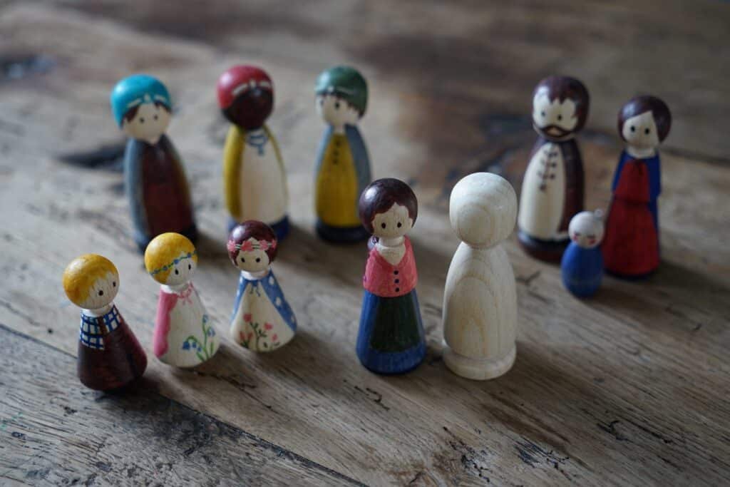 several hand painted wooden peg dolls on a wooden surface