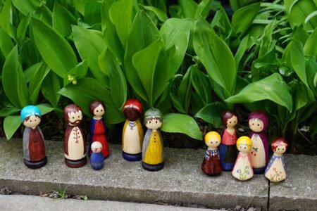 eleven colorful hand painted wooden peg dolls in a garden setting