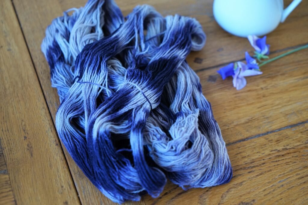 variegated hank of yarn in white and blue/purple on a wooden table