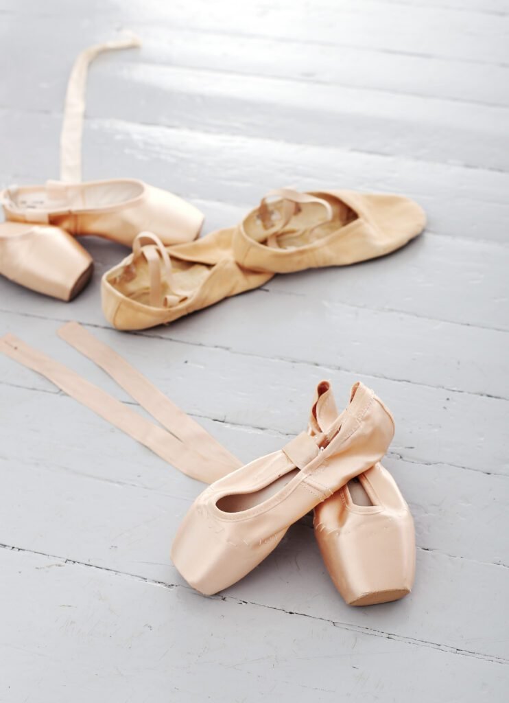 ballet shoes laying on a white wooden floor