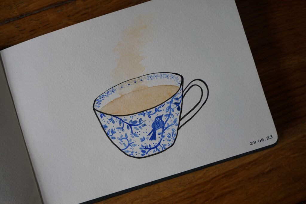 blue and white floral cup with steaming tea in it, watercolor and ink painting in a sketchbook