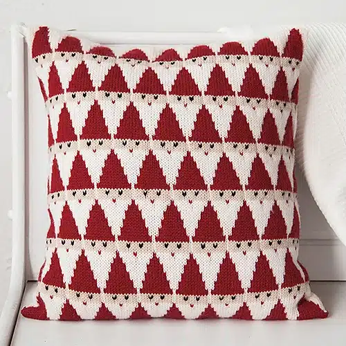 a handknitted pillow in red and white with a geometric santa pattern all over