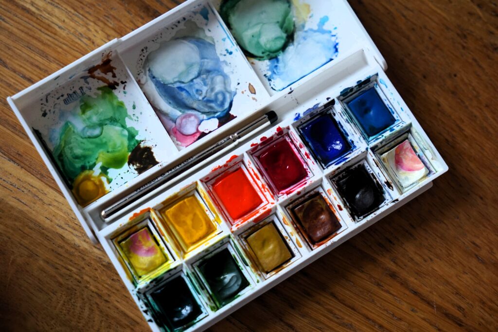 an open watercolor palette by winsor and newton on a wooden table.