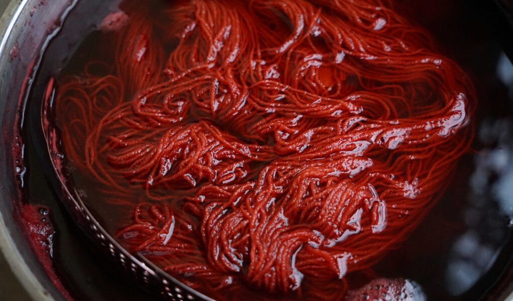 a skein of red yarn in a dyepot
